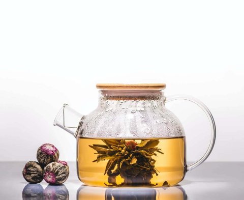 glass teapot of chinese flowering tea with tea balls on table